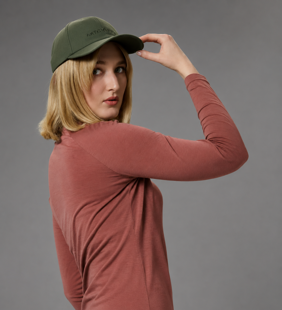 Model in pink long sleeve shirt and green cap
